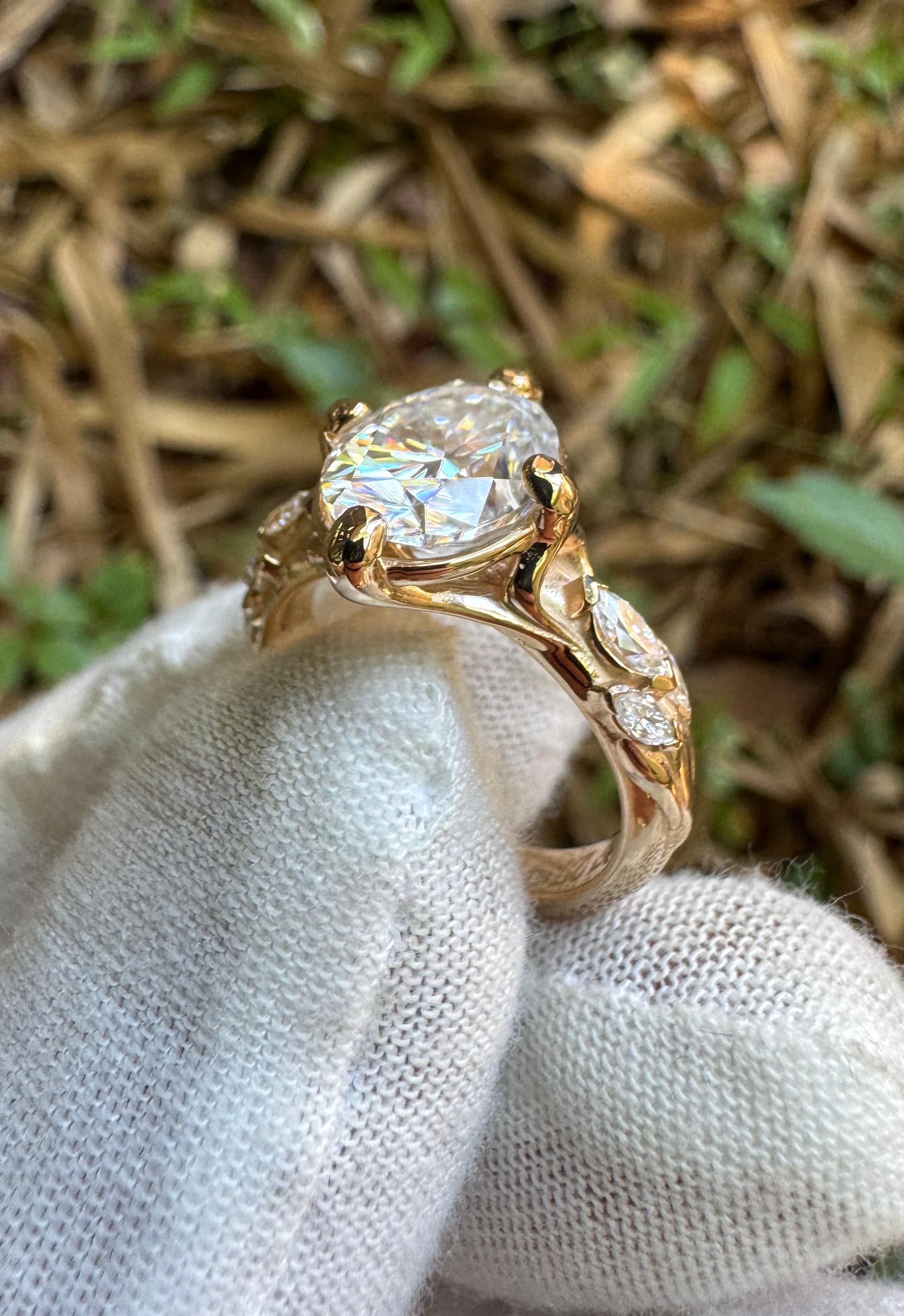 Gold engagement ring with oval diamond and marquise leaf details